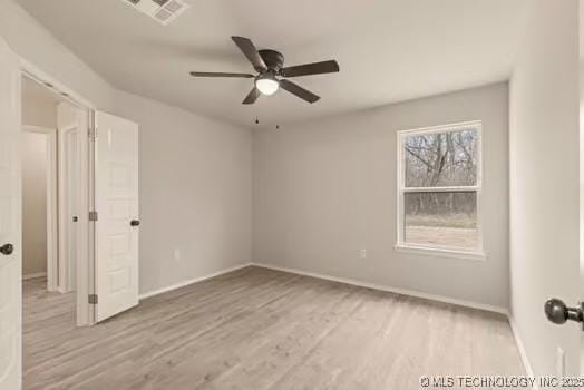 empty room with a ceiling fan, visible vents, baseboards, and wood finished floors