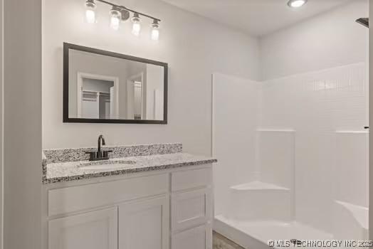 full bathroom featuring a shower and vanity