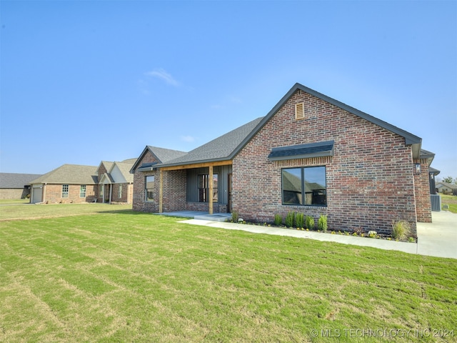 view of front of property featuring brick siding, a front lawn, and central air condition unit