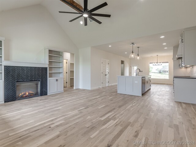 unfurnished living room featuring a tile fireplace, light hardwood / wood-style flooring, high vaulted ceiling, and ceiling fan