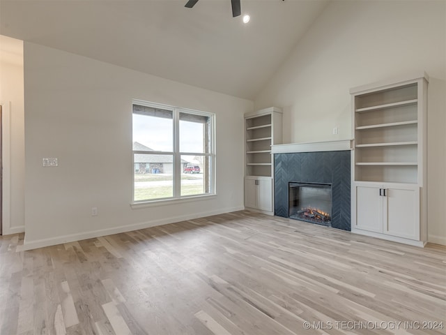 unfurnished living room with light hardwood / wood-style floors, ceiling fan, high vaulted ceiling, and a tiled fireplace