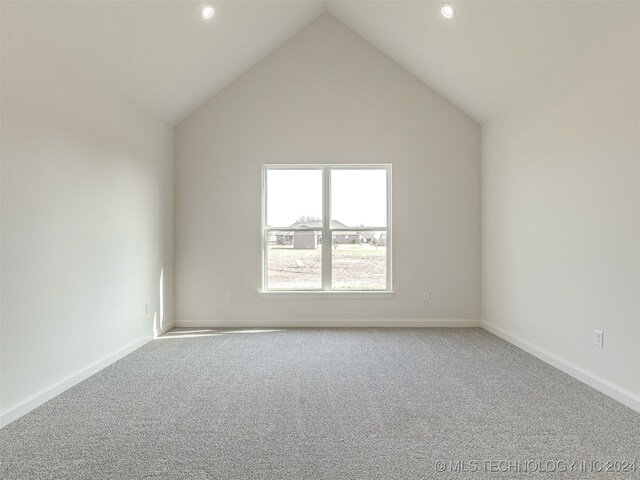 carpeted empty room with vaulted ceiling