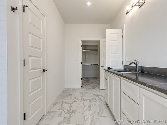 bathroom featuring baseboards, marble finish floor, a walk in closet, vanity, and recessed lighting