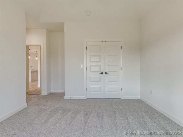 unfurnished bedroom featuring light carpet and a closet