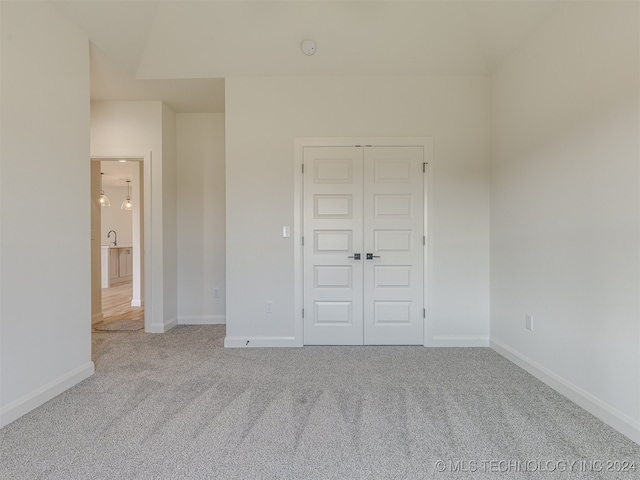 unfurnished bedroom with light carpet, baseboards, and a closet