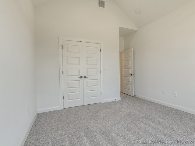 unfurnished bedroom featuring carpet flooring, a closet, and vaulted ceiling