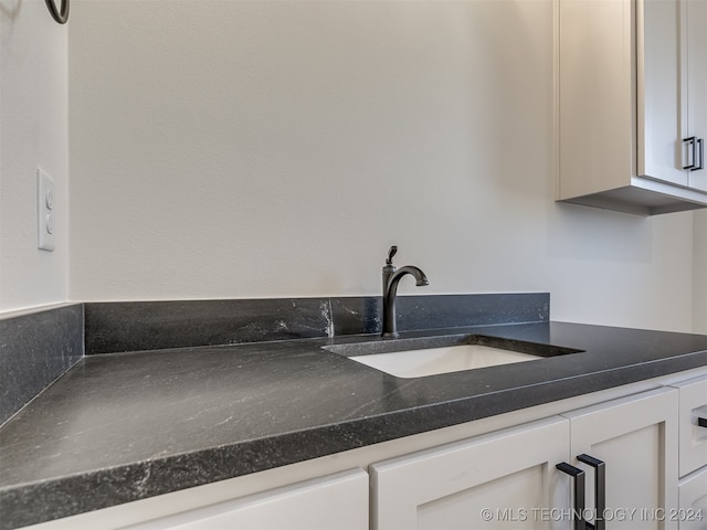 interior space featuring dark countertops, a sink, and white cabinets