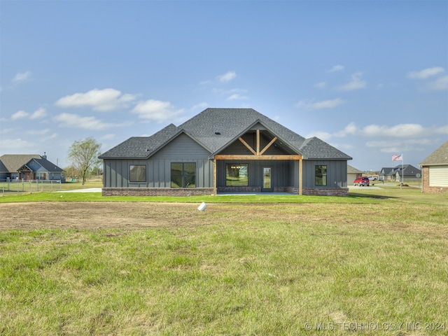 view of front of house featuring board and batten siding, a front yard, and a shingled roof