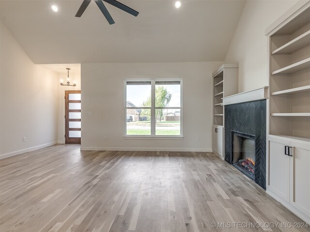 unfurnished living room featuring light wood-type flooring, built in shelves, ceiling fan with notable chandelier, and lofted ceiling