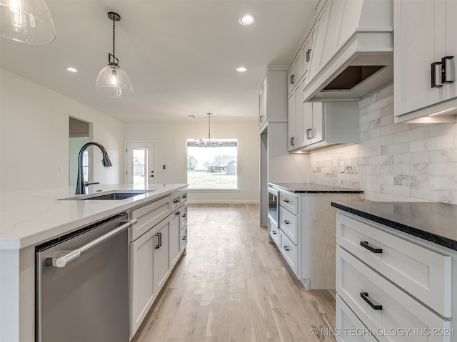 kitchen featuring a sink, white cabinets, stainless steel dishwasher, an island with sink, and pendant lighting