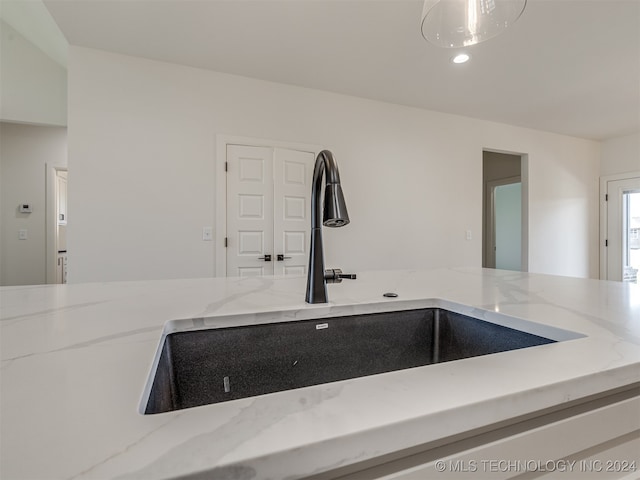 interior details featuring light stone countertops and sink