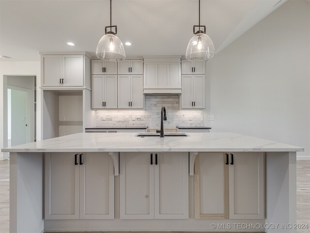 kitchen featuring decorative light fixtures, light stone countertops, and a large island