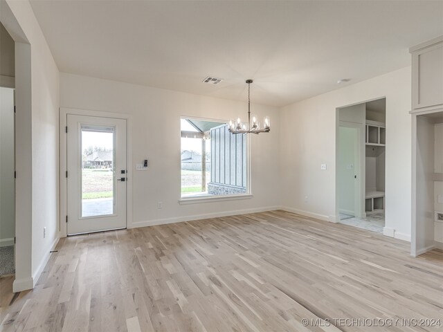 unfurnished dining area featuring light hardwood / wood-style floors and a chandelier