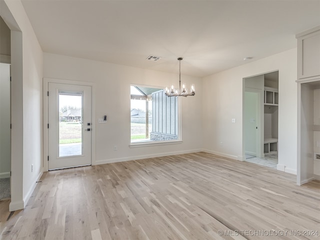 unfurnished dining area featuring light wood-style floors, visible vents, plenty of natural light, and a notable chandelier