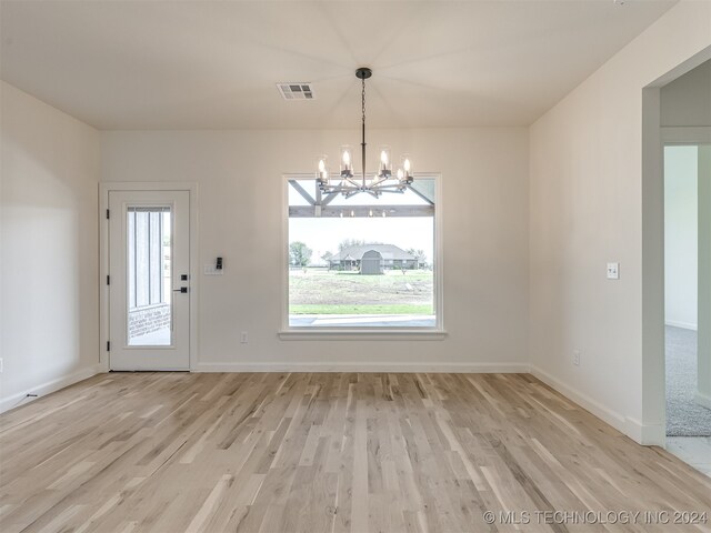 unfurnished dining area with a chandelier and light hardwood / wood-style flooring