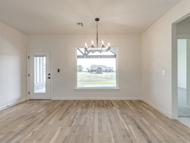 unfurnished dining area with a healthy amount of sunlight, light wood finished floors, visible vents, and a notable chandelier