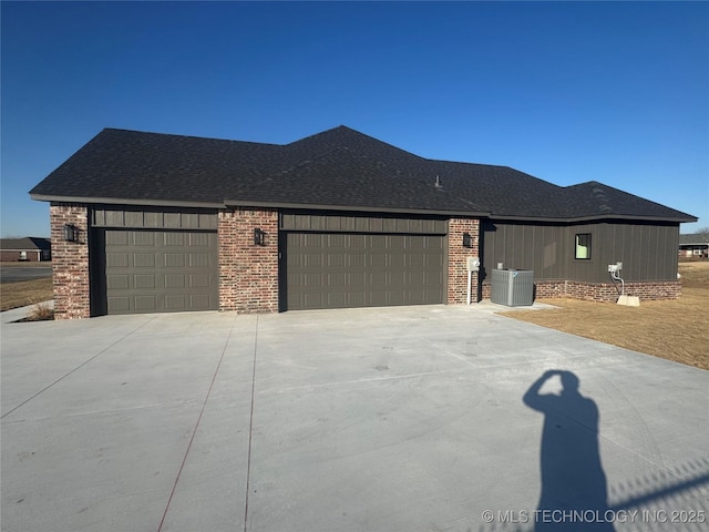 view of front of property featuring concrete driveway, central AC unit, roof with shingles, and an attached garage