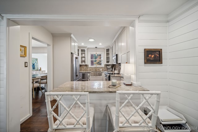 kitchen with white cabinetry, kitchen peninsula, appliances with stainless steel finishes, tasteful backsplash, and dark wood-type flooring