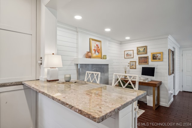 kitchen with white cabinets, light stone countertops, kitchen peninsula, and ornamental molding