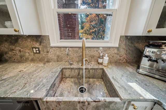 details featuring stone counters, white cabinetry, and sink