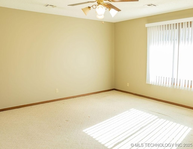 carpeted spare room featuring ceiling fan and baseboards