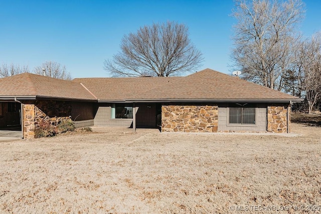 back of property with stone siding and a shingled roof