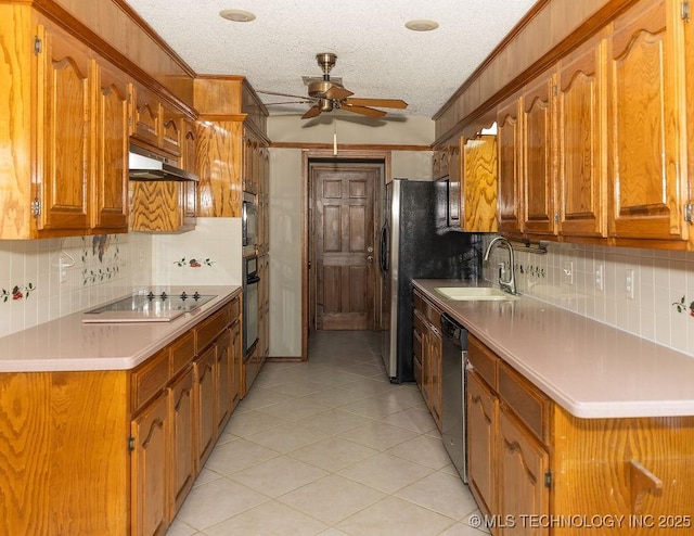 kitchen with a sink, black appliances, a ceiling fan, under cabinet range hood, and backsplash