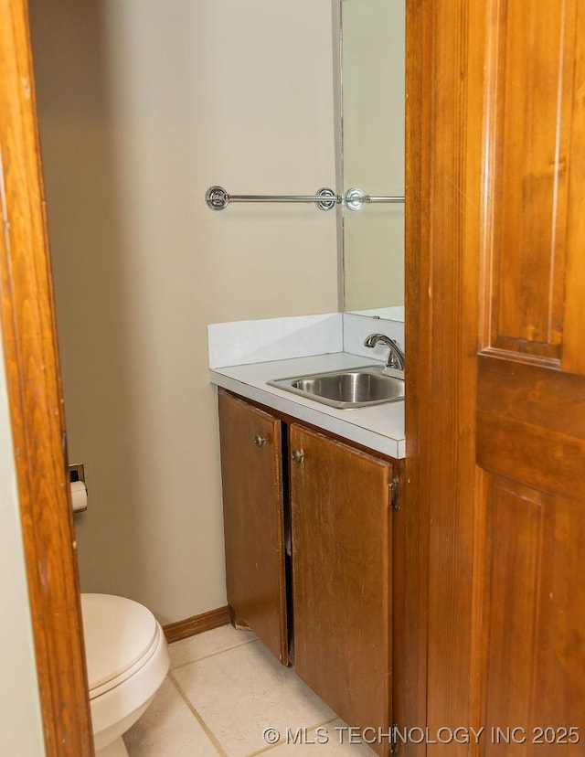 half bathroom featuring toilet, vanity, tile patterned floors, and baseboards