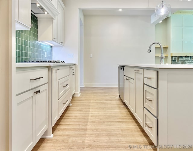 kitchen with tasteful backsplash, white cabinetry, light wood-type flooring, decorative light fixtures, and gas cooktop