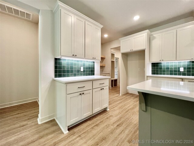 kitchen with white cabinetry, light hardwood / wood-style flooring, and backsplash