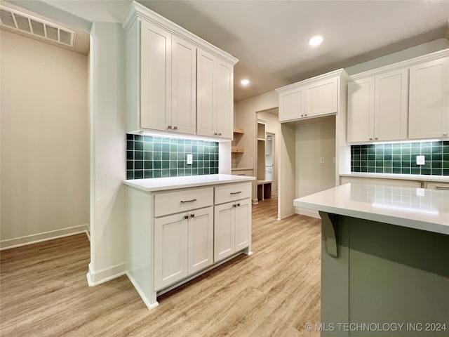 kitchen with backsplash, light hardwood / wood-style floors, and white cabinets