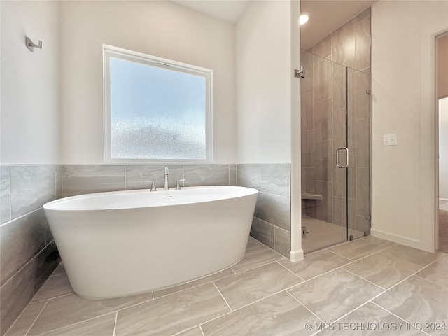 bathroom with tile walls, tile patterned flooring, and shower with separate bathtub