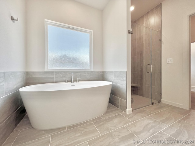 bathroom with tile walls and shower with separate bathtub