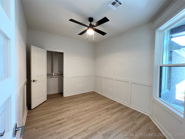 unfurnished bedroom featuring light hardwood / wood-style floors, ceiling fan, and a closet