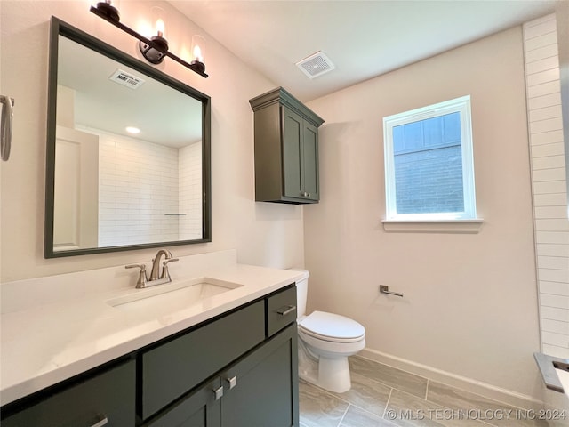 bathroom featuring toilet, vanity, and tiled shower