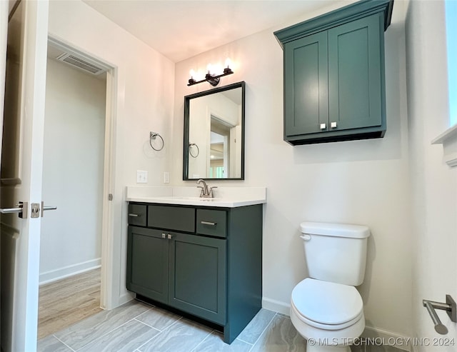 bathroom with toilet, vanity, and hardwood / wood-style flooring