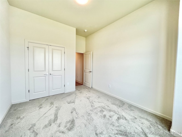 unfurnished bedroom featuring a closet and light carpet