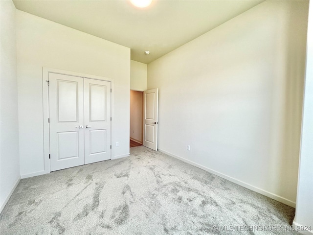 unfurnished bedroom with light colored carpet and a closet