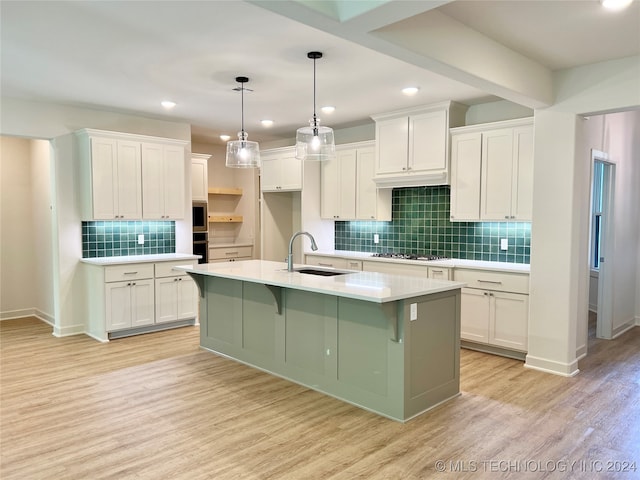 kitchen with an island with sink, light hardwood / wood-style floors, white cabinetry, and sink