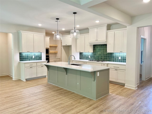 kitchen with white cabinetry, sink, and a center island with sink