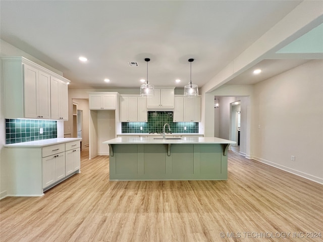 kitchen with light wood-type flooring, white cabinets, and a kitchen island with sink