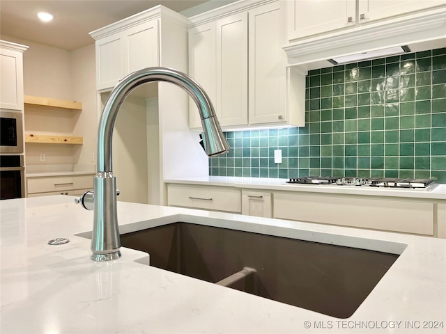 kitchen with sink, white cabinetry, light stone counters, tasteful backsplash, and appliances with stainless steel finishes