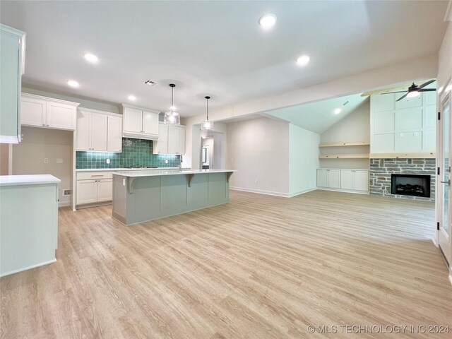 kitchen featuring white cabinets, a center island with sink, and light wood-type flooring