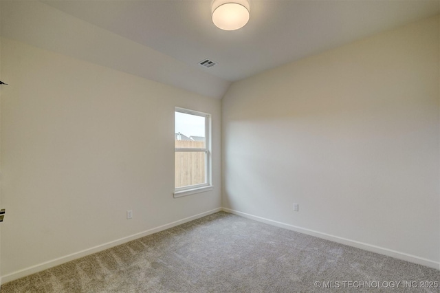 spare room with carpet floors, lofted ceiling, visible vents, and baseboards