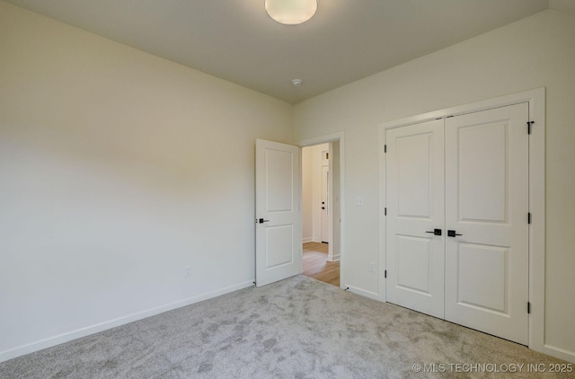unfurnished bedroom featuring baseboards, carpet flooring, and a closet