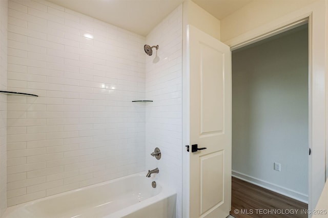 bathroom with shower / bathing tub combination, wood finished floors, and baseboards