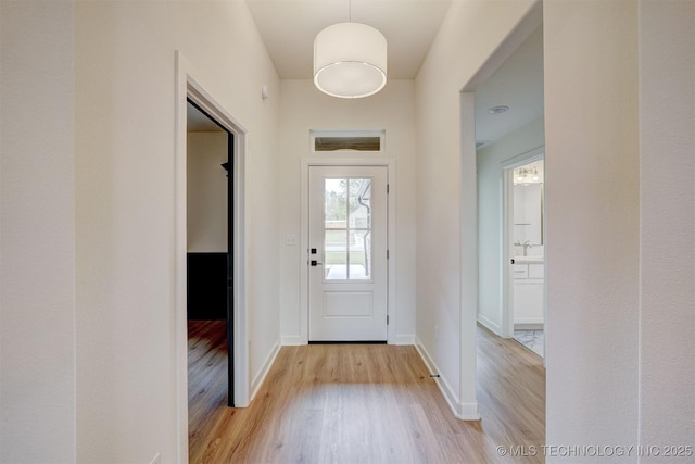 doorway featuring baseboards, wood finished floors, and a sink