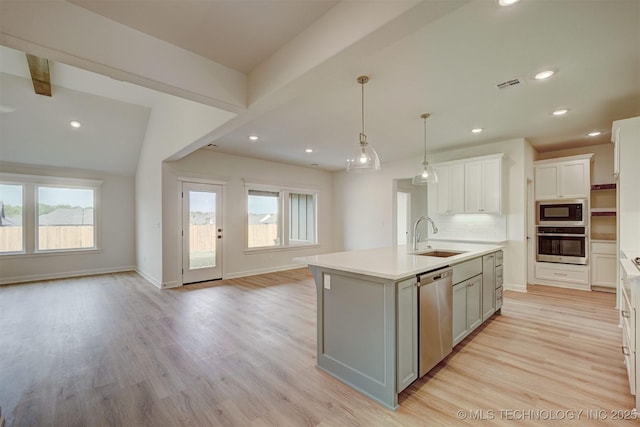 kitchen featuring an island with sink, visible vents, a sink, appliances with stainless steel finishes, and open floor plan