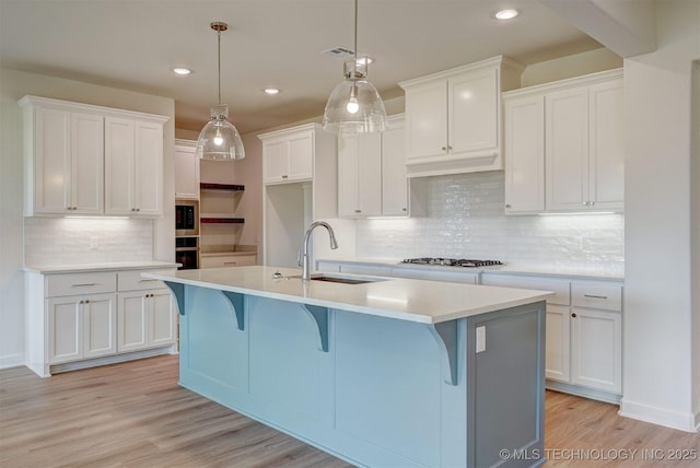 kitchen featuring a sink, a center island with sink, tasteful backsplash, recessed lighting, and white cabinetry