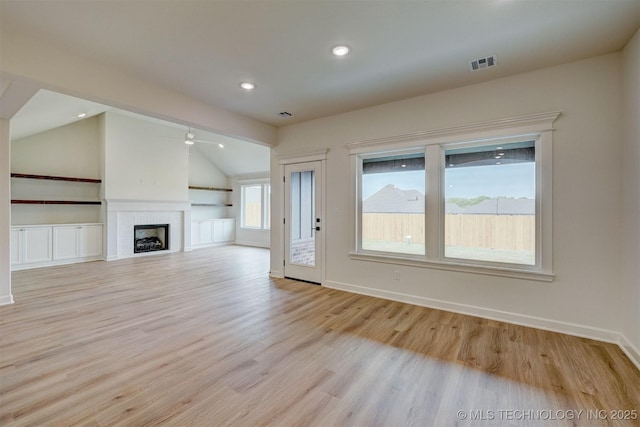 unfurnished living room with light wood-type flooring, baseboards, visible vents, lofted ceiling, and a ceiling fan